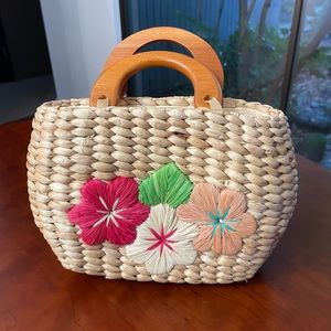 Cute straw/raffia handbag with zipper closure on top and double plastic handles.